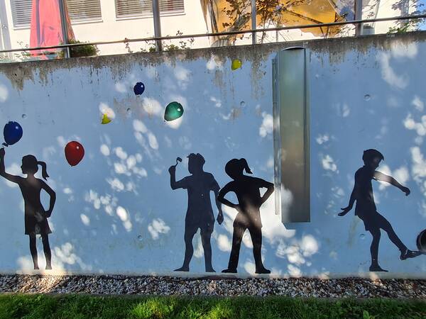 Schwarze Schatten von Kindern an der Wand, die spielen und Ballons steigen lassen.