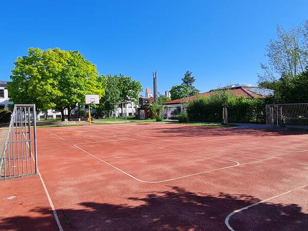 Pausenhof mit Fußballplatz, Fahrradstrecke und Basketballkorb.