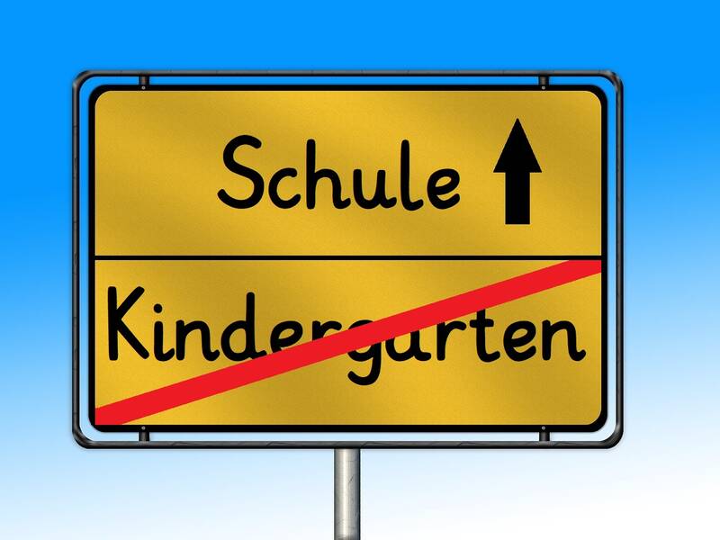 Ortsschild, das den Wechsel vom Kindergarten zur Schule zeigt.
