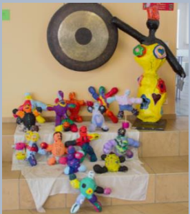 Figuren aus Pappmaché nach Phalle vor Gong und großer Figur in Aula.
