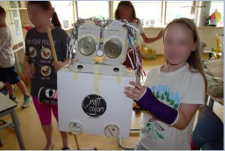 Schüler neben Roboter aus Müll in der Hand.