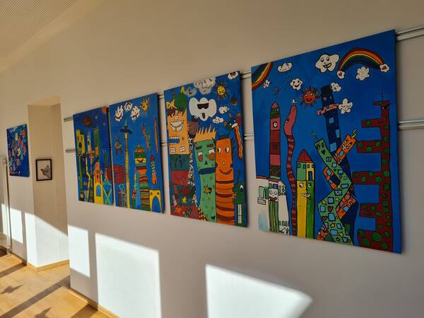 Gemalte Gebäude nach James Rizzi auf Leinwänden.