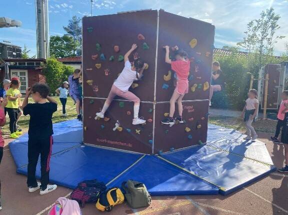 Kinder klettern an einer mobilen Boulderwand.